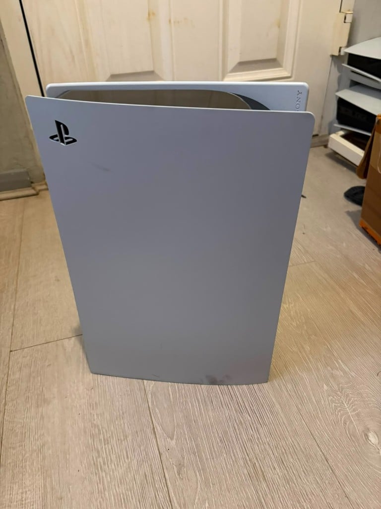 White PlayStation 5 console standing on a wooden floor