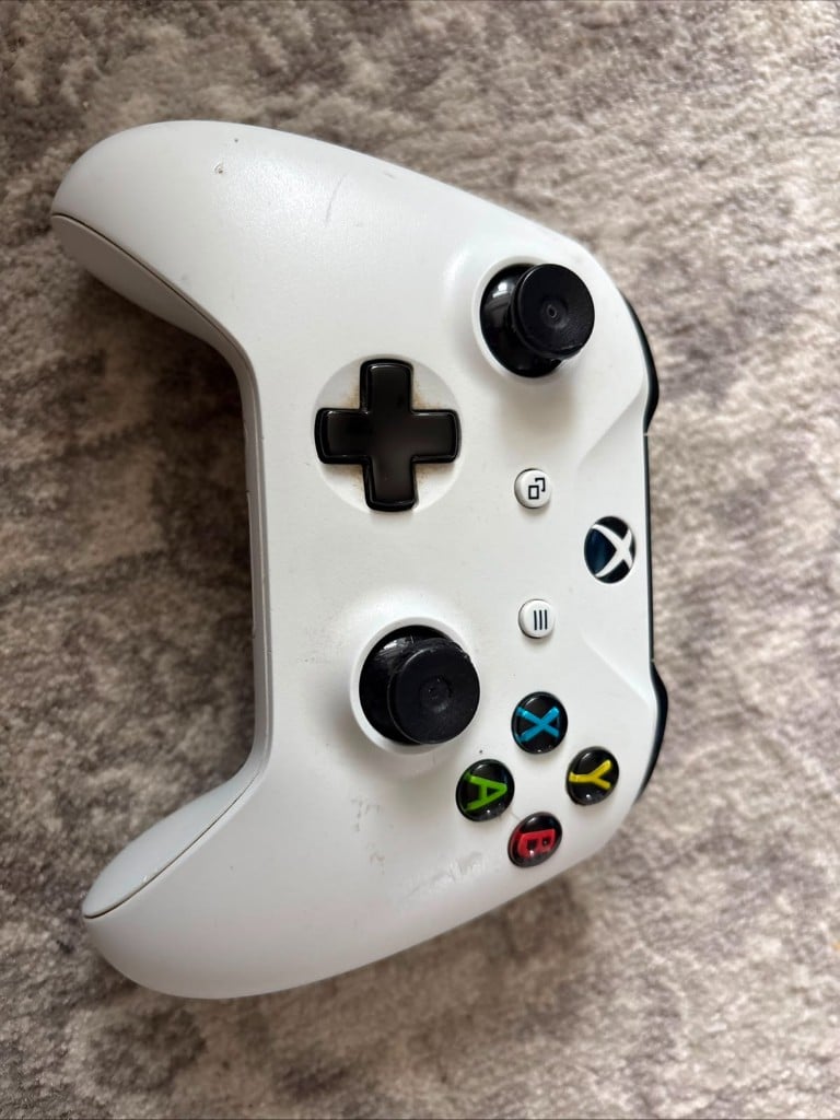 White Xbox wireless controller on grey carpet